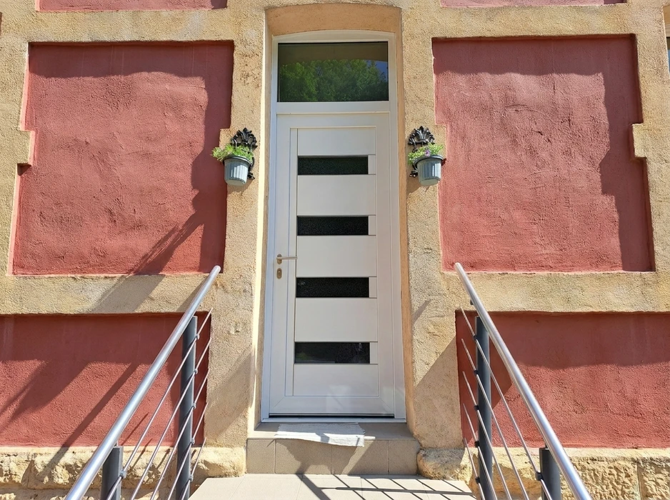 Entrée extérieure d'une maison avec une porte d'entrée moderne blanche à quatre inserts vitrés translucides et imposte vitrée