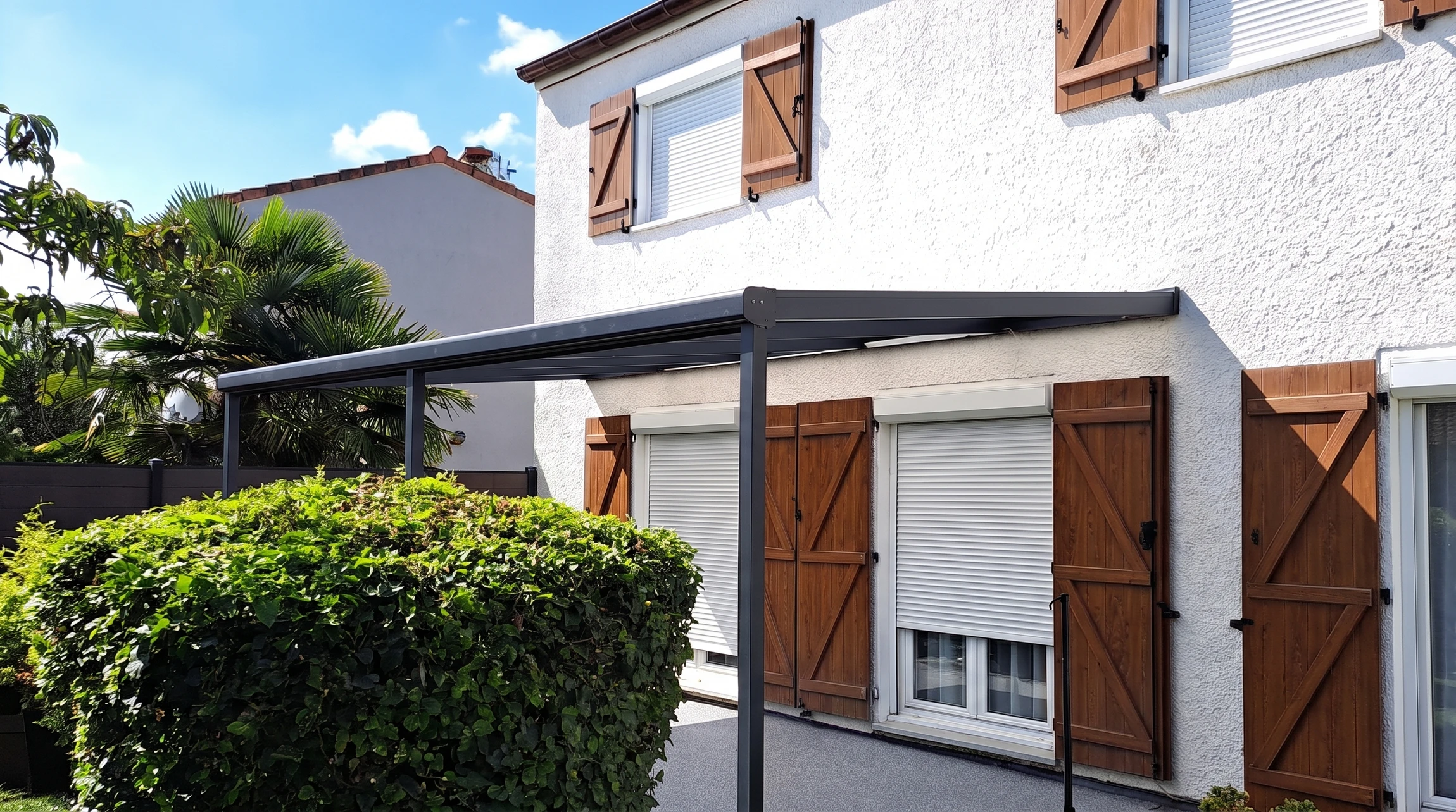 Terrasse couverte adossée à une maison individuelle à enduit blanc, volets bois style traditionnel français