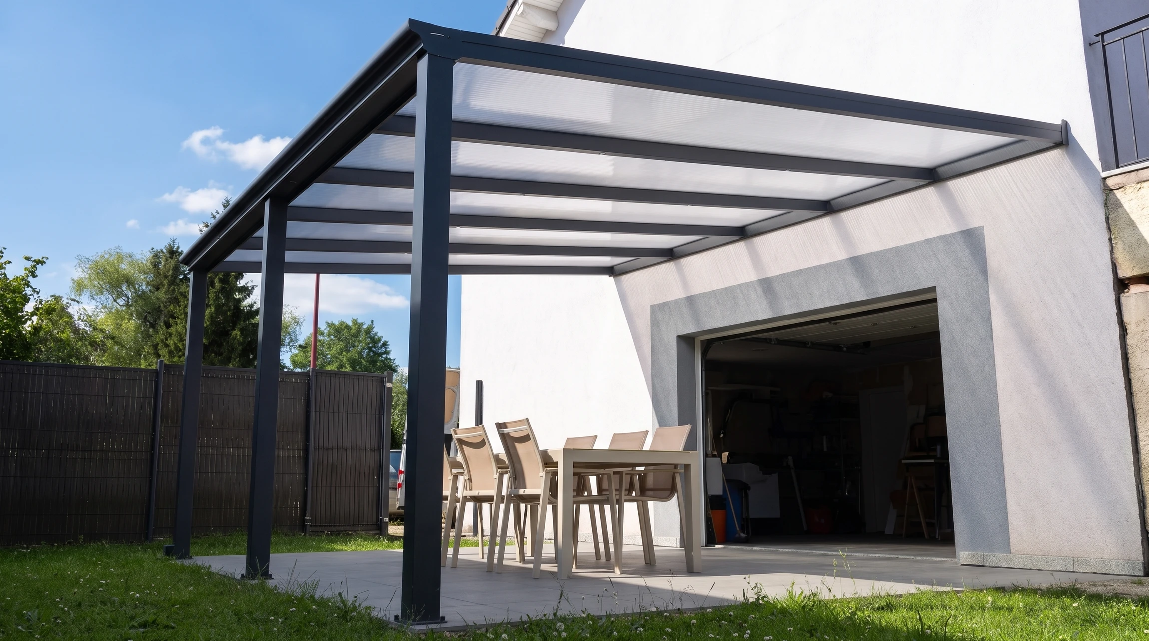 Terrasse couverte moderne attenante à une maison, avec pergola aluminium anthracite à toit polycarbonate translucide