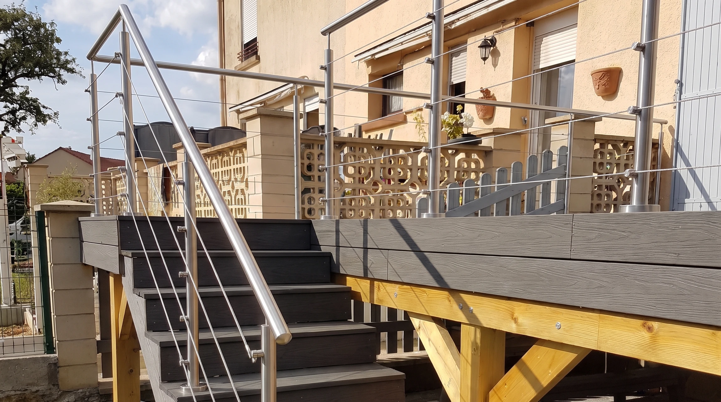 Terrasse extérieure surélevée avec escalier d'accès, composite gris anthracite, structure en bois massif traité