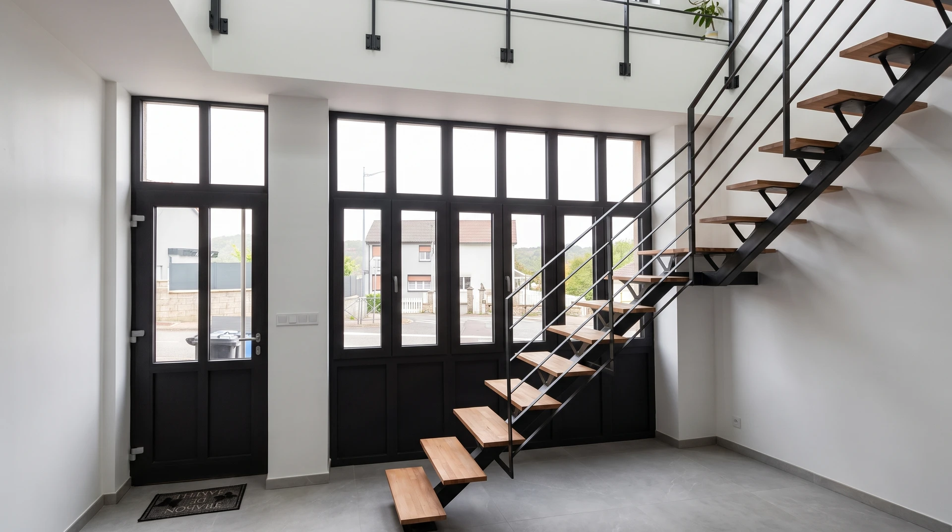 Porte d'entrée contemporaine en aluminium laquée anthracite RAL 7016, avec vitrage triangulaire asymétrique et incrustations décoratives dorées en V