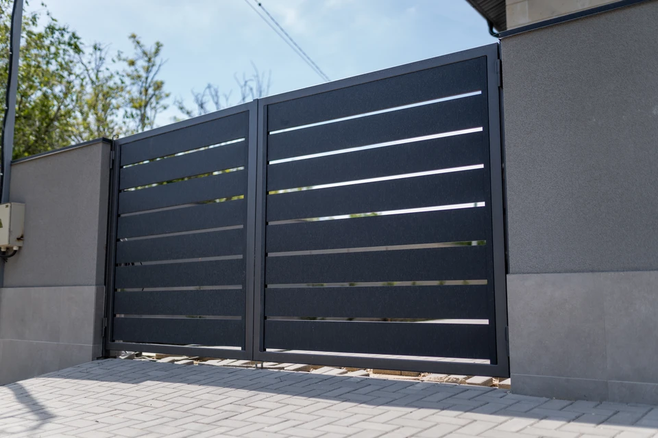 Scène extérieure résidentielle avec portail coulissant automatique en aluminium beige partiellement ouvert sur allée pavée en briques