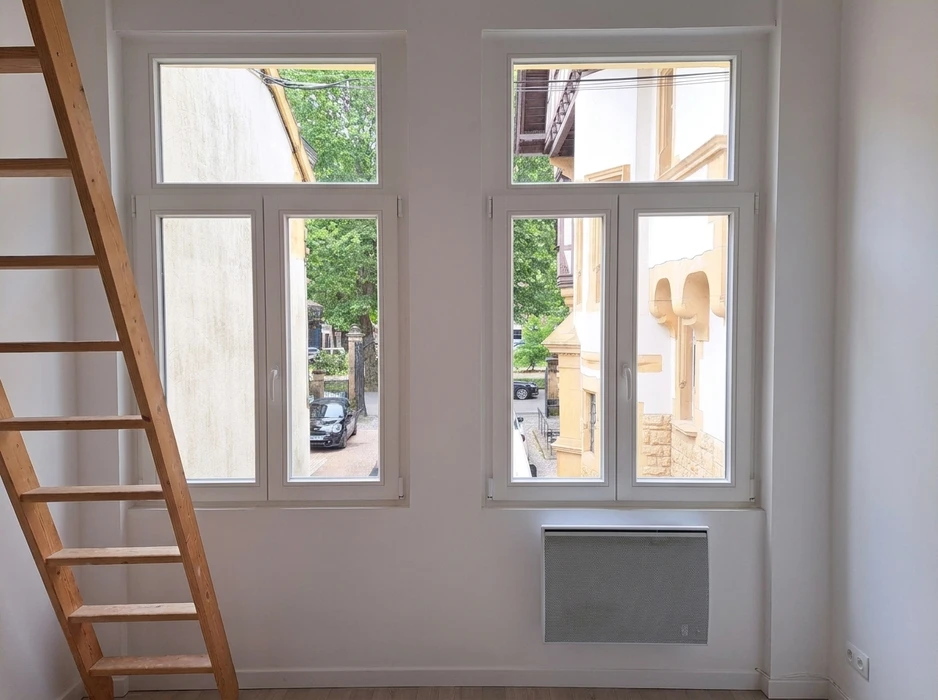 Entrée extérieure d'une maison avec une porte d'entrée moderne blanche à quatre inserts vitrés translucides et imposte vitrée
